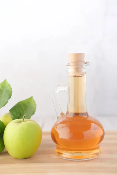 Cuka apel dalam botol kaca dengan apel hijau segar di atas meja — Stok Foto