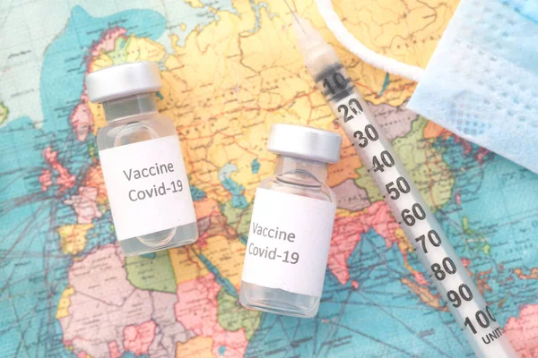 Close-up van het coronavirusvaccin en de spuit op een reiskaart — Stockfoto