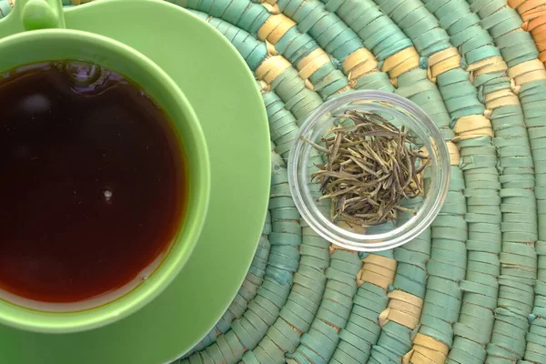 Vista superior de chá verde e folha de ervas em uma tigela de vidro pequena na mesa — Fotografia de Stock