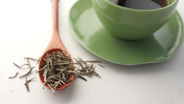 Вид зверху на зелений чай і трав'яний лист у маленькій скляній мисці на столі — стокове відео