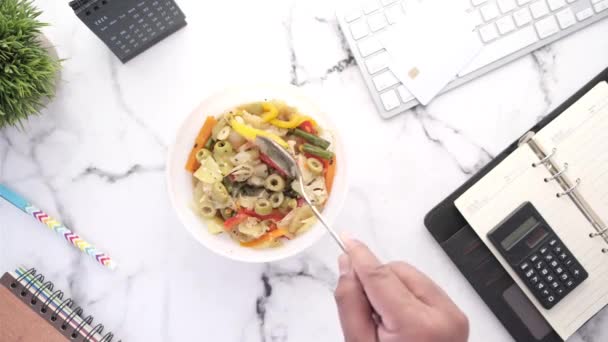 Joven comiendo ensalada fresca mientras trabaja en el ordenador portátil — Vídeo de stock