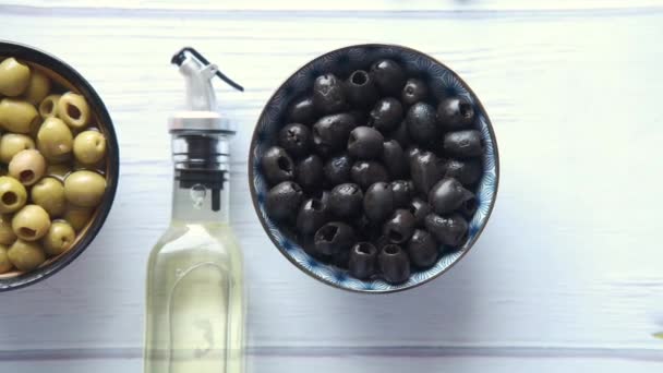 Bottle of olive oil and fresh olive in a container on wooden table — Stock Video