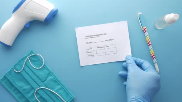 Cartão de registro de vacinação, higienizador de mãos e máscara no fundo de cor — Vídeo de Stock