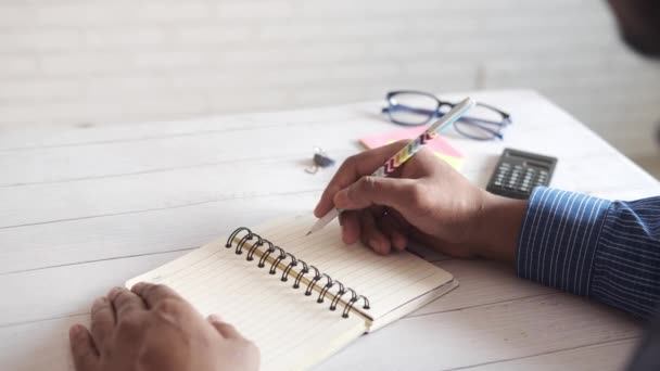 Vista trasera de la escritura manual del hombre en el bloc de notas. — Vídeo de stock