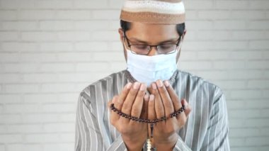 Yüz maskeli müslüman adam ramazan boyunca el ele dua ediyor., 