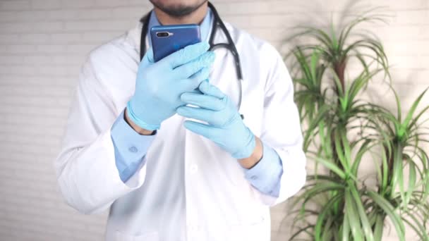 의사들은 스마트폰을 사용하여 보호 장갑을 끼고 있다. — 비디오