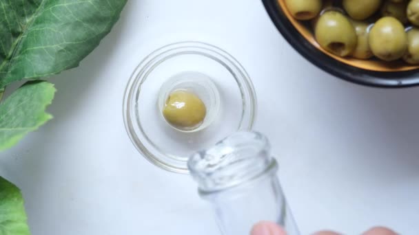 Garrafa de azeite e azeitona fresca em um recipiente sobre fundo branco . — Vídeo de Stock