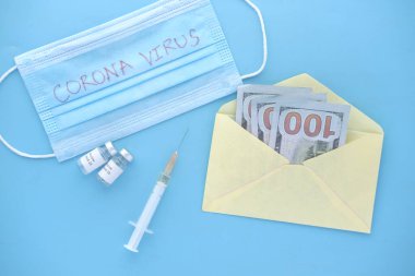 Coronavirus aşısı, şırınga ve nakit parayla mavi arka plan.