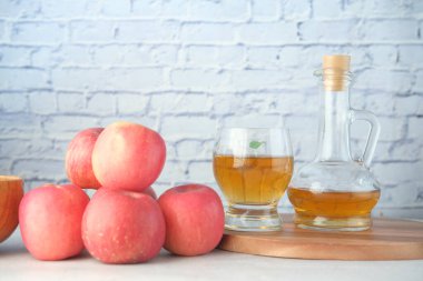 Cam şişede elma sirkesi ve masada taze yeşil elma. 