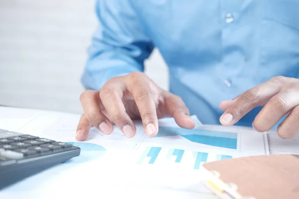 Fiatal férfi elemzése pénzügyi adatok papíron az asztalon — Stock Fotó