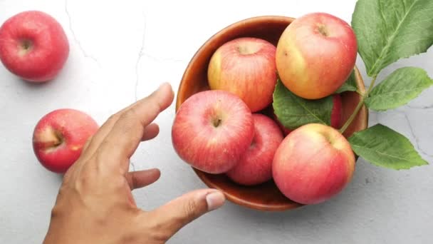 Ręka zbierać świeże jabłko w misce na drewnianym stole — Wideo stockowe