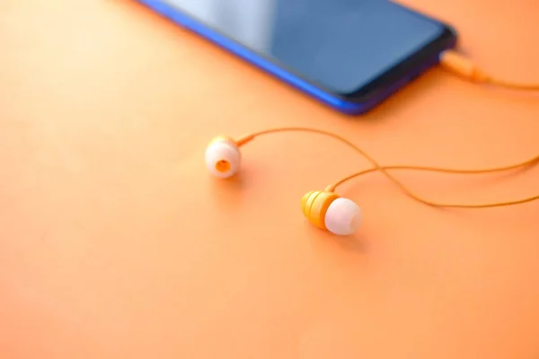 Téléphone intelligent avec écran vide, écouteur sur fond orange — Photo