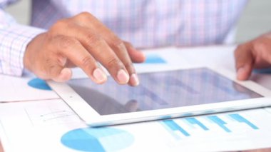 Adam el ile ofis masasında dijital tablet üzerinde çalışıyor, kendi yarattığı grafiği kullanarak. 