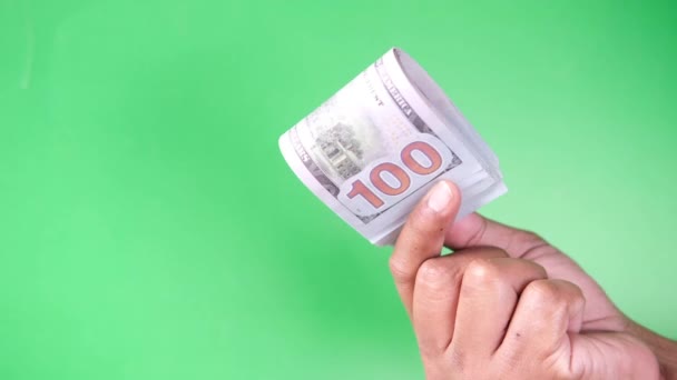 Крупним планом рука людини підраховує 100 доларів США готівкою на зеленому фоні — стокове відео