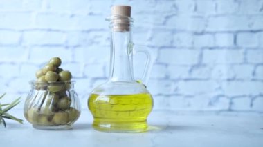 Bir şişe zeytinyağı ve taze zeytin ahşap bir masada. .