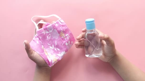Barn hand hålla kirurgisk ansiktsmask och rengöringsmedel gel på rosa — Stockvideo