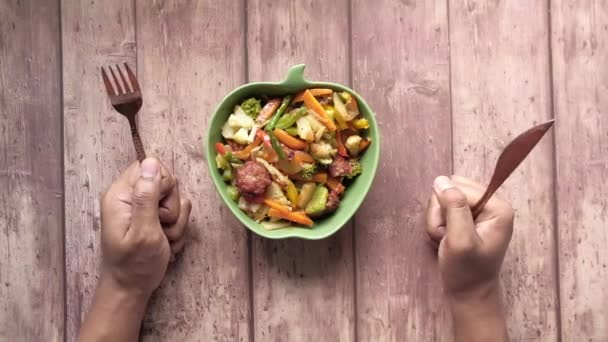Joven con tenedor esperando en un plato lleno de verduras — Vídeo de stock
