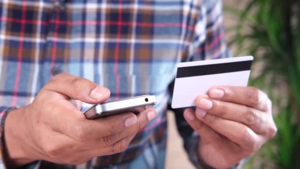 Mann hält Kreditkarte in der Hand und kauft mit Smartphone online ein — Stockvideo