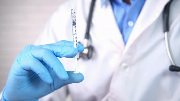 Tangan dokter dalam sarung tangan medis memegang jarum suntik. — Stok Video
