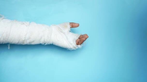Поврежденная рука с повязкой на синем фоне — стоковое видео