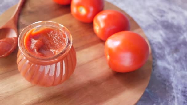 Salsa de tomate en un frasco pequeño con tomate fresco en la mesa — Vídeos de Stock