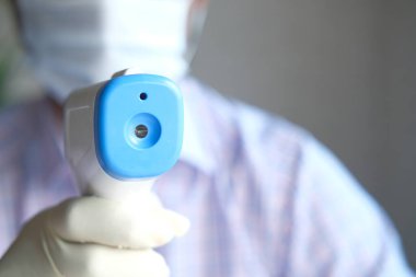 Sıcaklığı ölçmek için el ele tutuşan kızılötesi termometre.