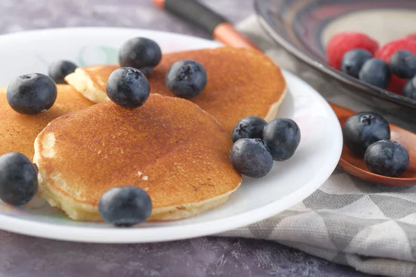 Leckeres Essen mit Beeren und Pfannkuchen in Schüssel auf schwarzem Hintergrund — Stockfoto