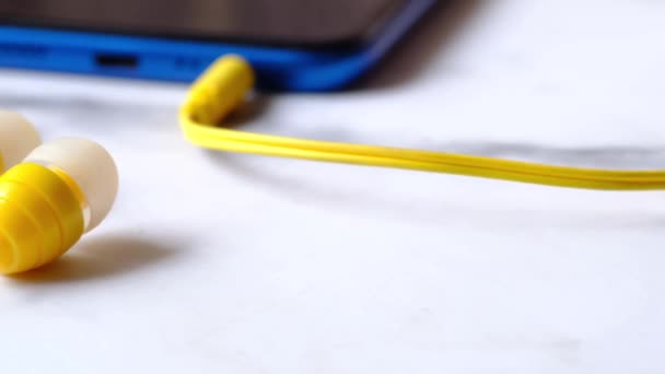 Детальне зображення смартфона з навушниками на білому тлі — стокове відео