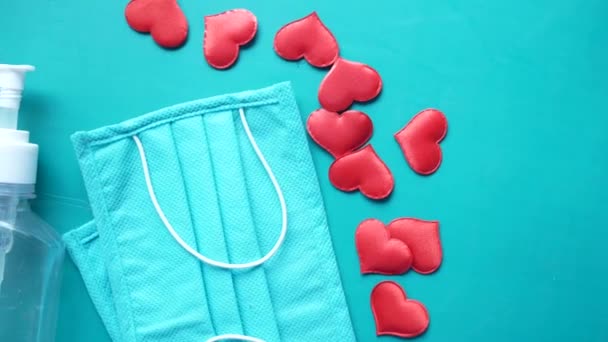 Máscaras cirúrgicas com forma de coração e higienizador de mão no fundo de cor — Vídeo de Stock