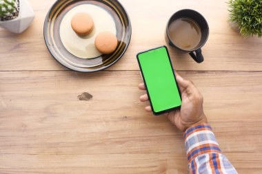 Ofis masasında akıllı telefon kullanan bir adamın üst görüntüsü. 