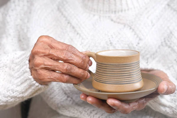 Mão de mulheres seniores segurando uma xícara de chá verde — Fotografia de Stock