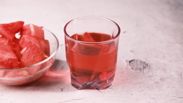 Zbliżenie plastra arbuza wodnego i szklanki soku z arbuza wodnego na stole — Wideo stockowe