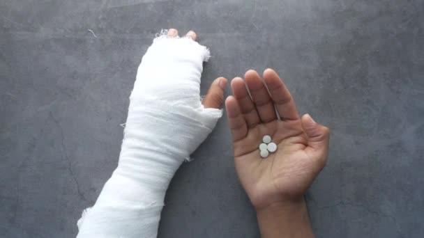 Injured painful hand with bandage and medical pills on hand — Stock Video