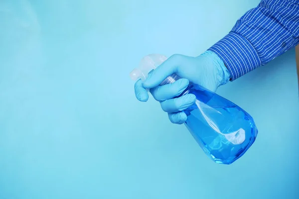 Mano en guantes de goma azul que sostiene la botella del aerosol con espacio de copia — Foto de Stock