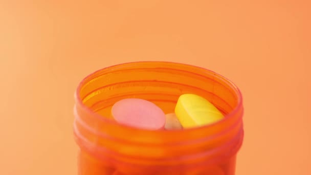 Close up of medical pills and capsules in a small container on blue background — Stock Video