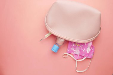 Cerrahi maskeler, termometre ve el dezenfektanı küçük çantada. 