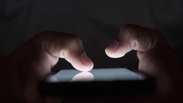 Primer plano de la mano del hombre joven usando el teléfono inteligente en la noche — Vídeos de Stock