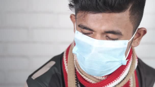 Omtänksam ung asiatisk man med skyddande ansiktsmask tittar bort — Stockvideo