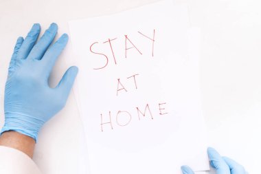 Doktor elinde kağıt tutan lateks eldivenlerle evde oturuyor. .