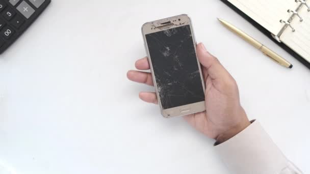 Nahaufnahme der Hand eines Mannes mit kaputtem Smartphone auf weißem Hintergrund — Stockvideo