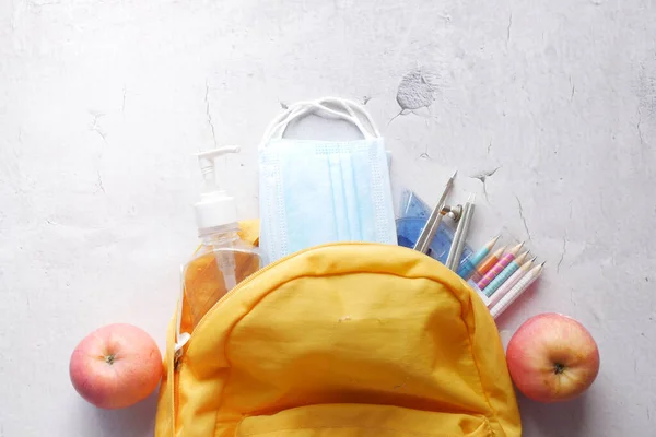 Student school bag pack with sanitizer, a face mask on table