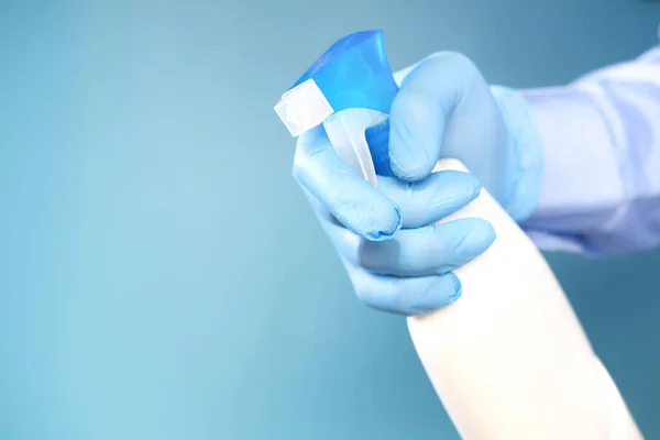 Hand in blauwe rubberen handschoenen met spuitfles en kopieerruimte — Stockfoto