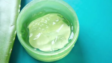 Taze aloe vera dilimlenmiş ve plastik kapta sıvı jel beyaz arka planda 