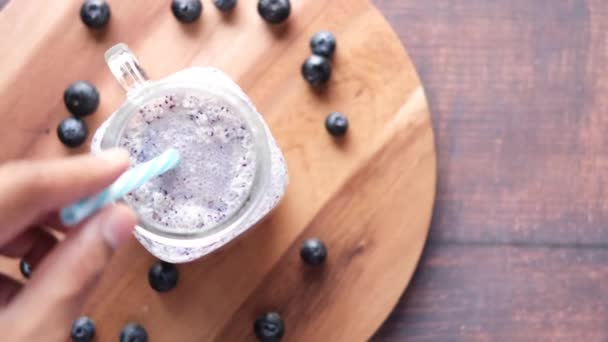 Blauwe bessen milkshake in een glas op tafel — Stockvideo