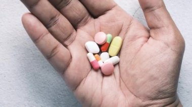 Avucunun içinde bir sürü ilaç ve kapsül var. 