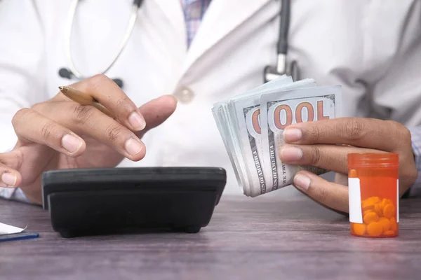 Mano del médico sosteniendo efectivo y utilizando la calculadora —  Fotos de Stock