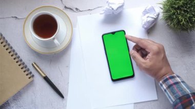 Ofis masasında akıllı telefon kullanan bir adamın üst görüntüsü. 