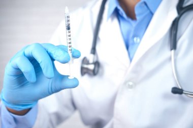 Doktor elinde şırınga tutan tıbbi eldivenler getirdi..