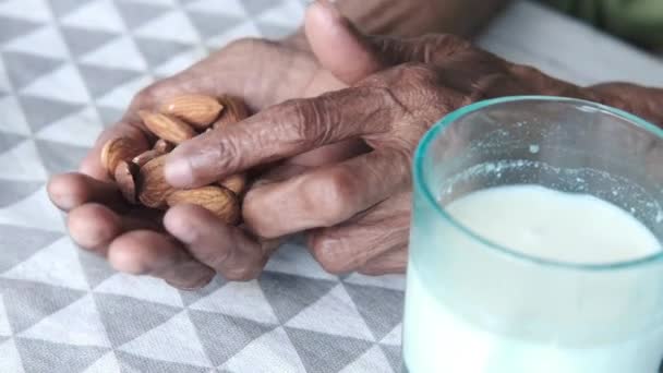 Cerrar las mujeres mayores mano sosteniendo nuez de almendra — Vídeo de stock