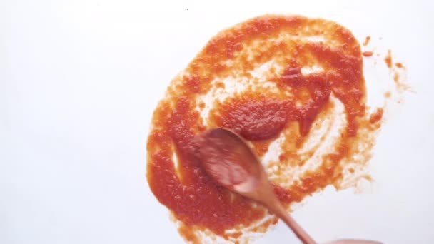 Salsa de tomate y una cuchara de madera sobre fondo blanco — Vídeo de stock